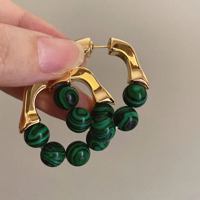 Gold hoop earrings with green marbled beads, statement accessory.