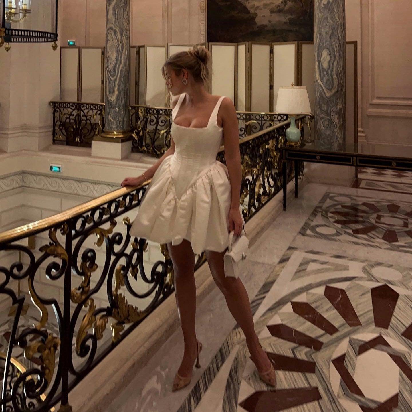 White satin evening dress with a full skirt and strappy shoulders.