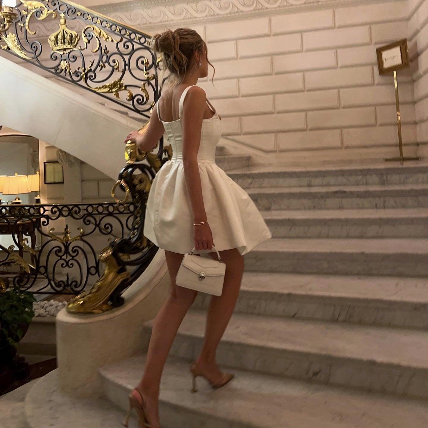 White mini dress with strappy heels and a small handbag for an evening look.