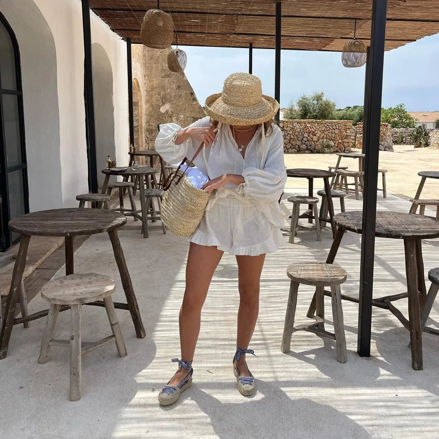 White blouse and shorts with a straw hat and bag.