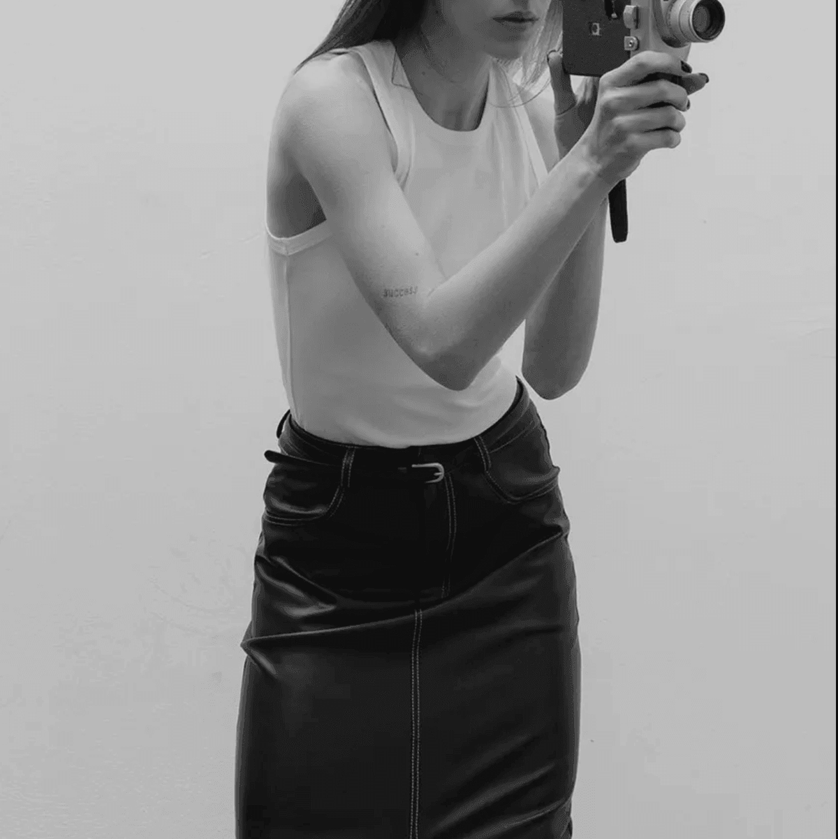 White sleeveless top paired with a black leather skirt, casual chic look.
