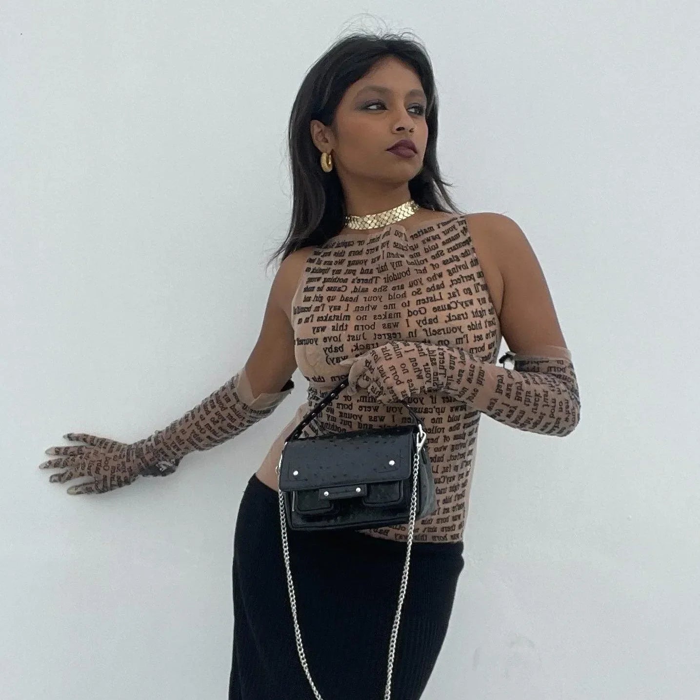 Text-printed mesh top with matching gloves and black handbag, fashion-forward statement look