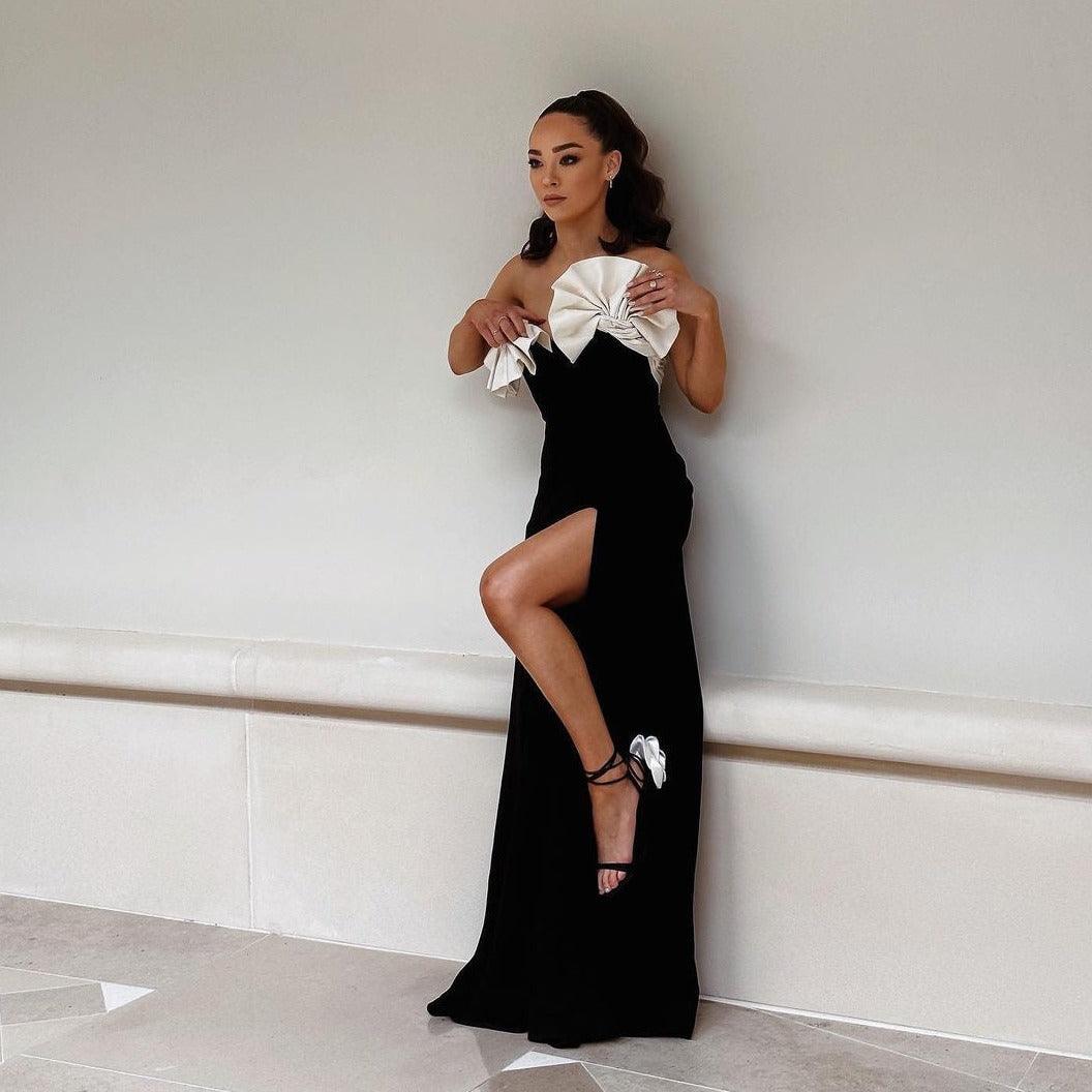 Strapless black evening gown with dramatic white bow detailing and thigh-high slit, formal event