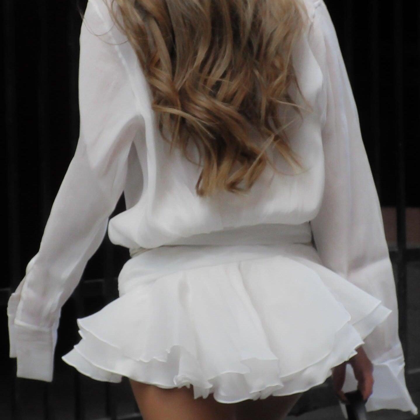 White ruffled mini skirt with sheer long-sleeve blouse, chic party outfit