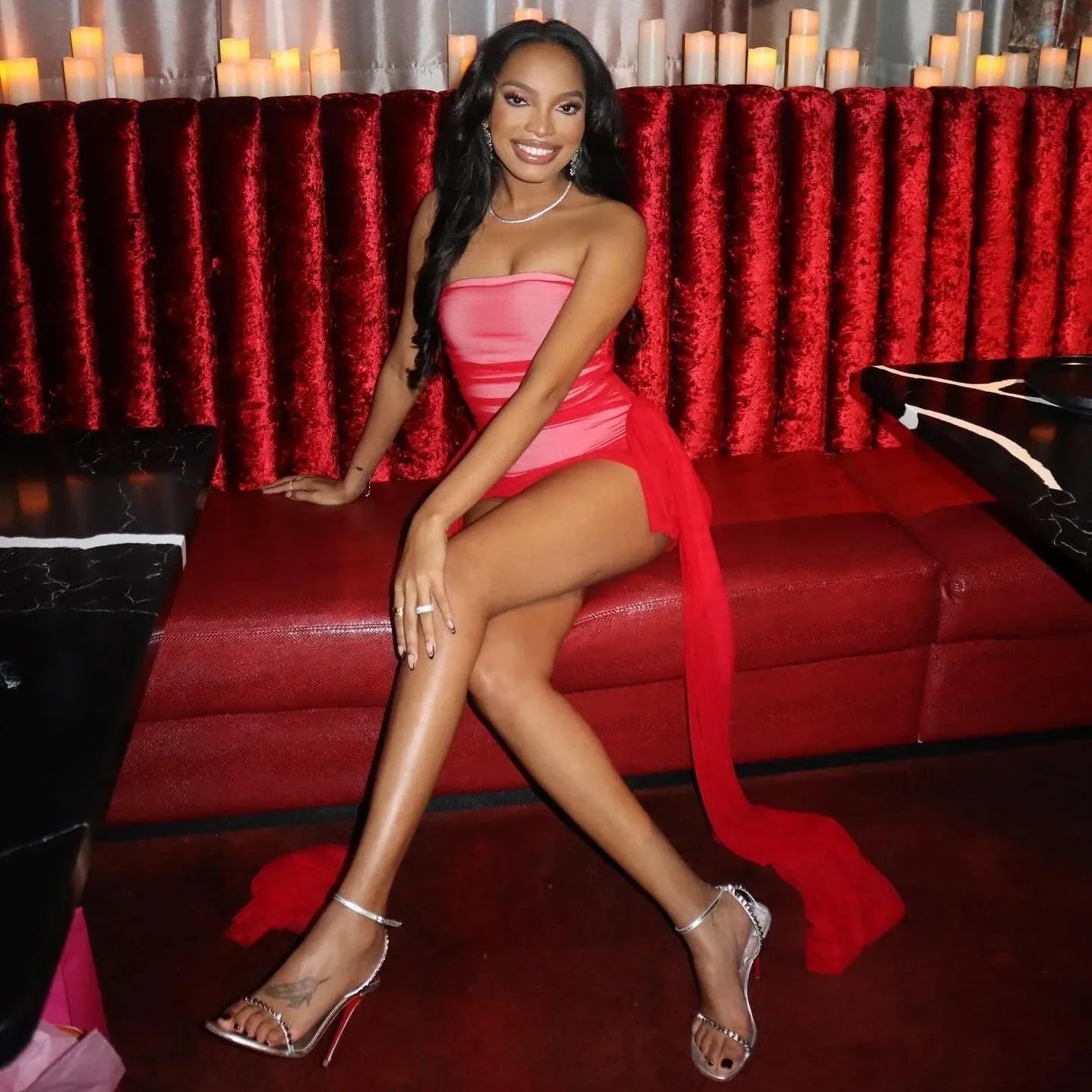 Strapless ruched mini dress with sheer overlay and high slit, paired with strappy heels for a