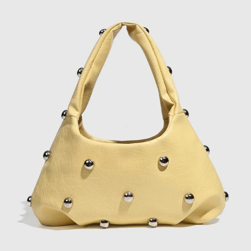 Yellow handbag with metallic stud embellishments, trendy accessory for day or night.