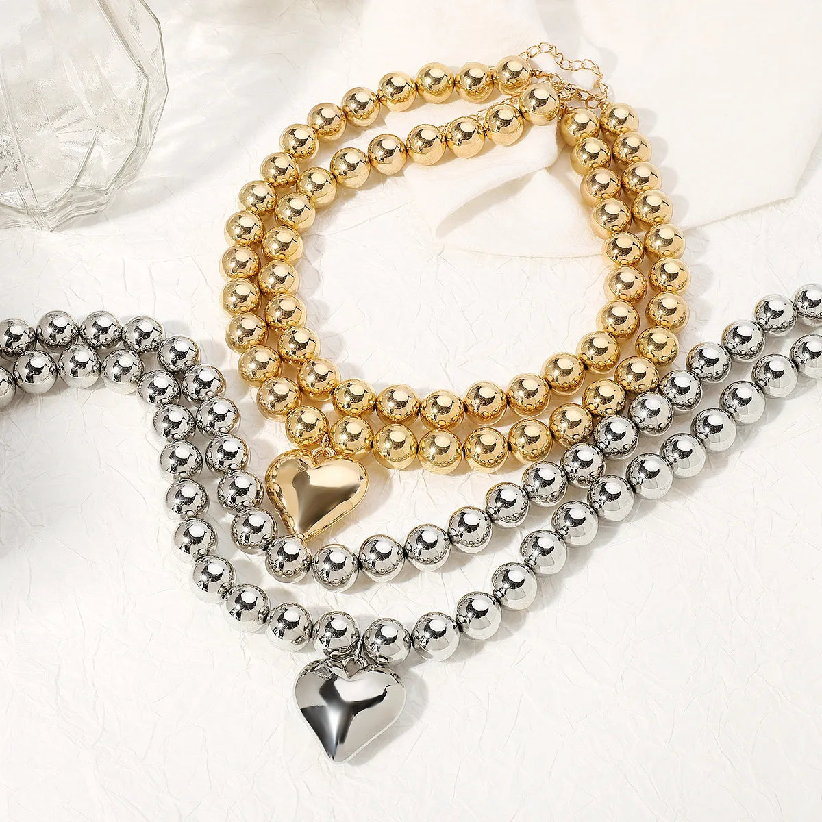 Gold and silver beaded necklaces with heart pendants.