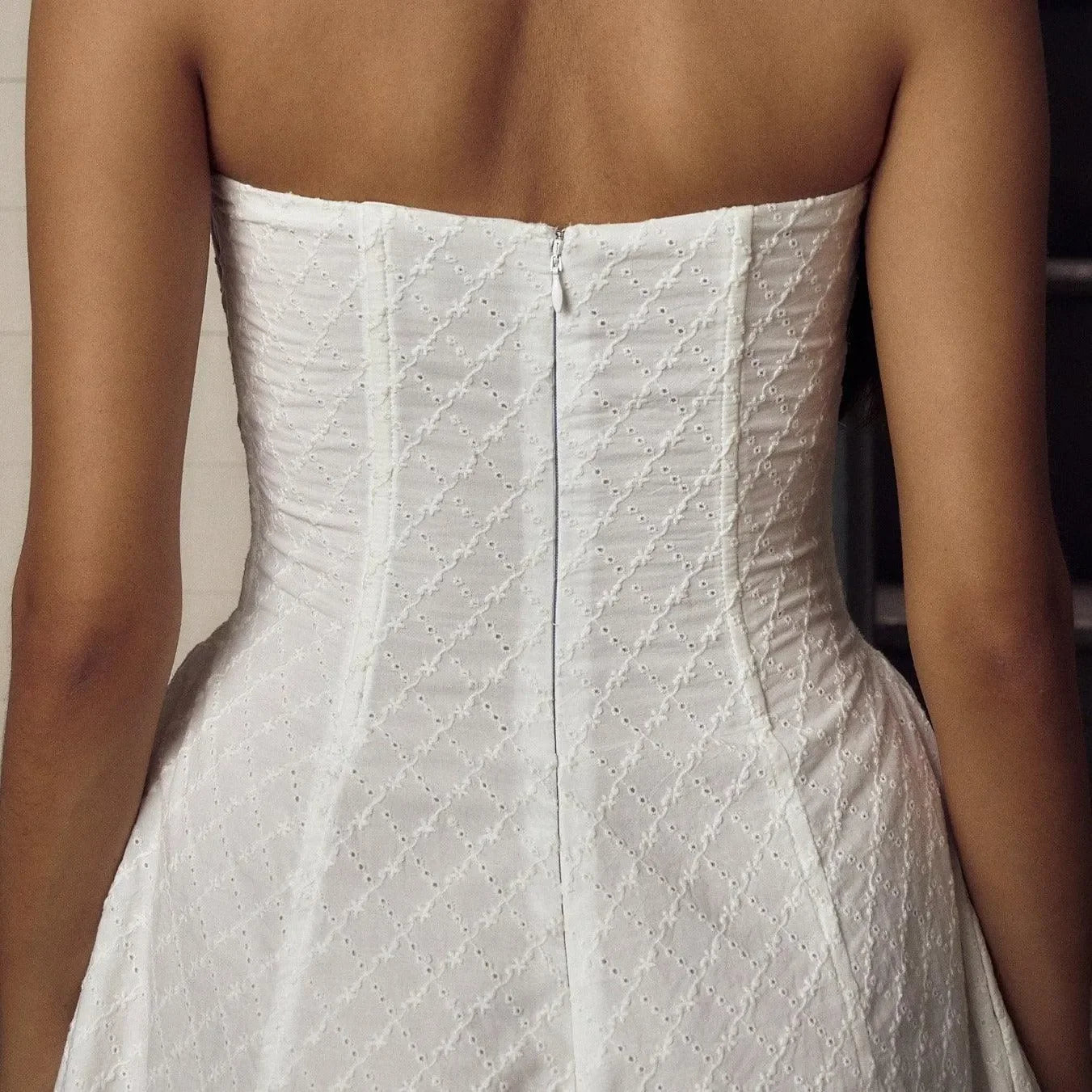 Strapless textured white dress with corset-style back, elegant evening wear.