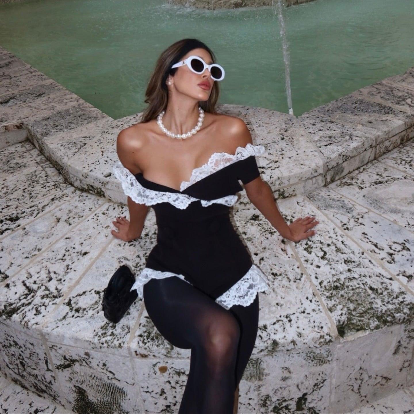 Off-shoulder black dress with white lace detailing, elegant evening look