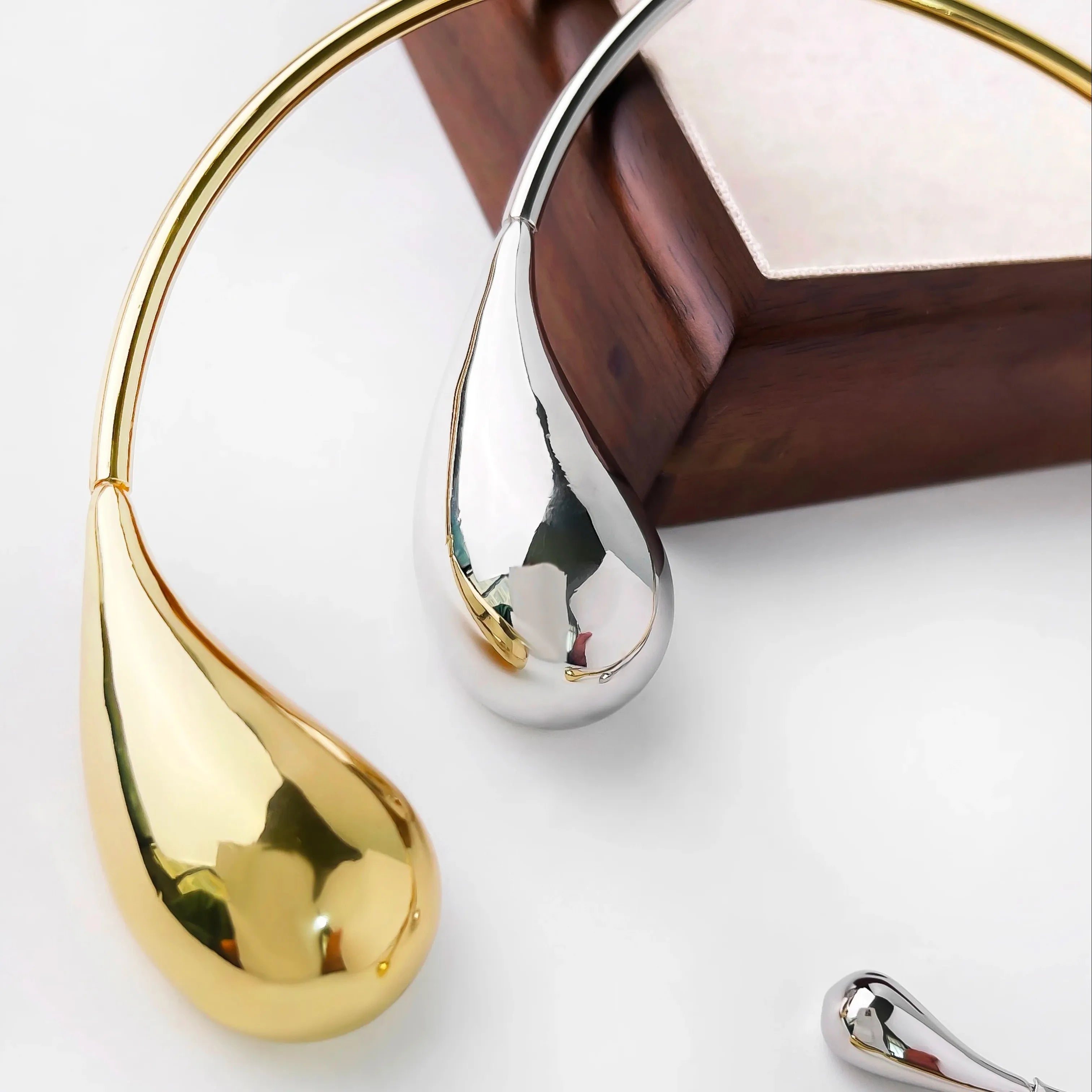 Gold and silver teardrop-shaped bracelets, statement accessories.