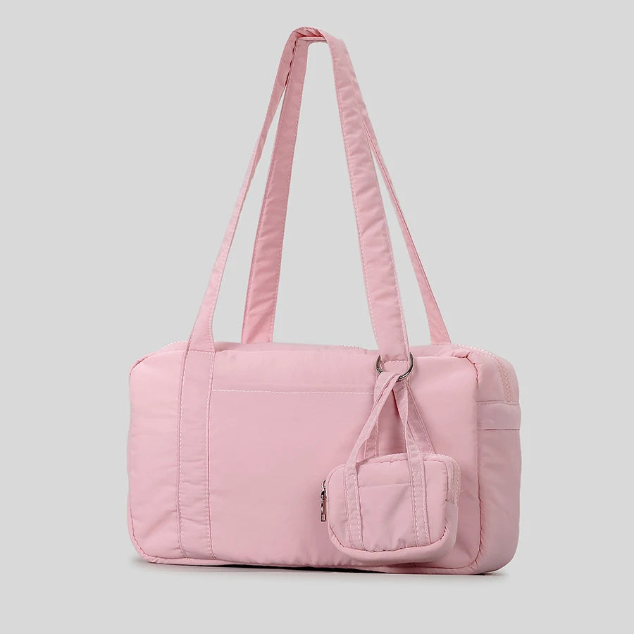 Light pink quilted shoulder bag with long straps and small attached pouch, casual accessory.