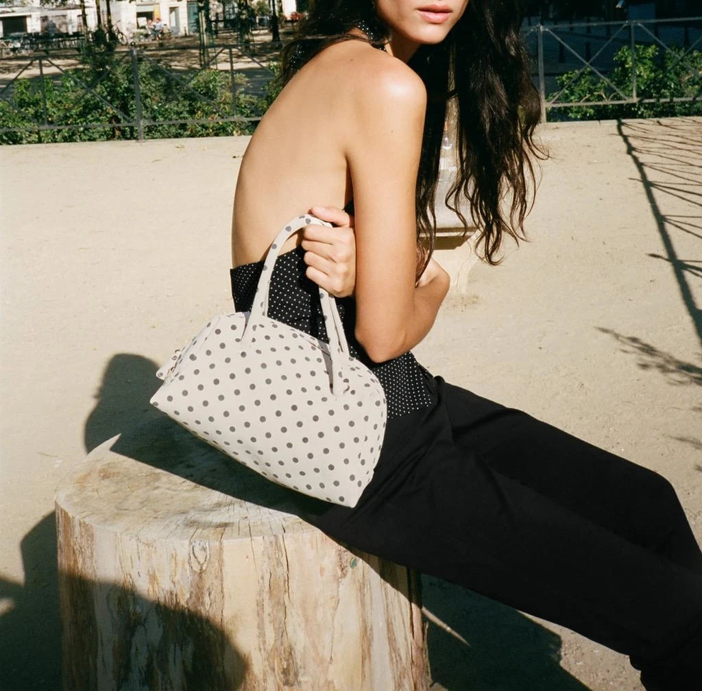 Polka dot handbag with structured handles, casual chic accessory.