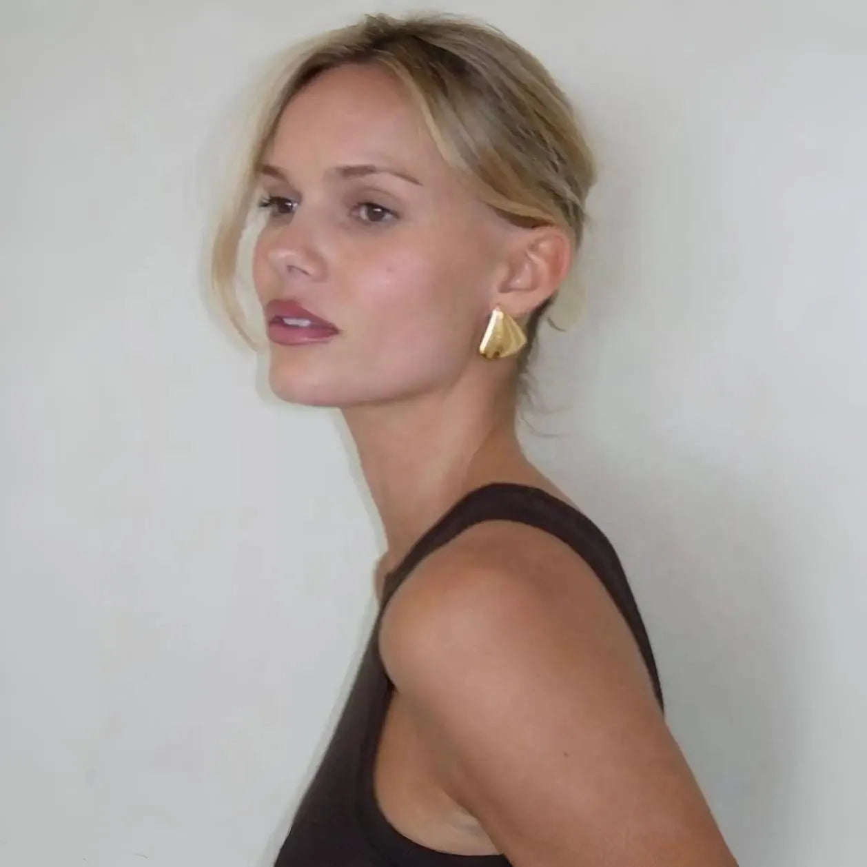 A sleeveless top with gold geometric earrings, minimalist fashion accessory styling.