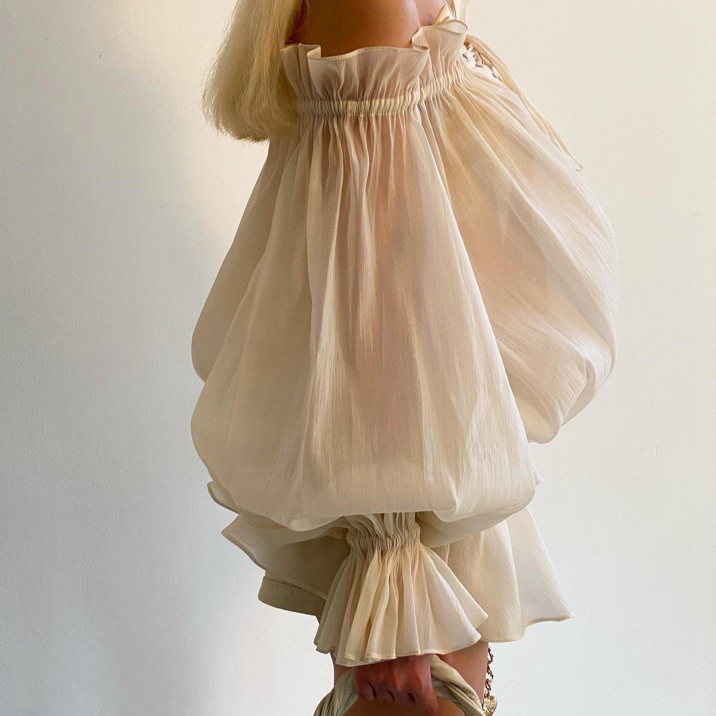 Sheer ruched puff-sleeve top with ruffled details.
