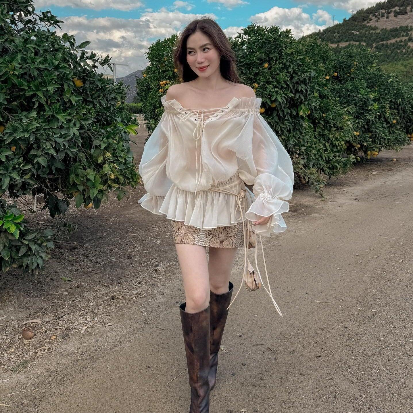 Sheer off-shoulder blouse with a lace-up front and snakeskin mini skirt.