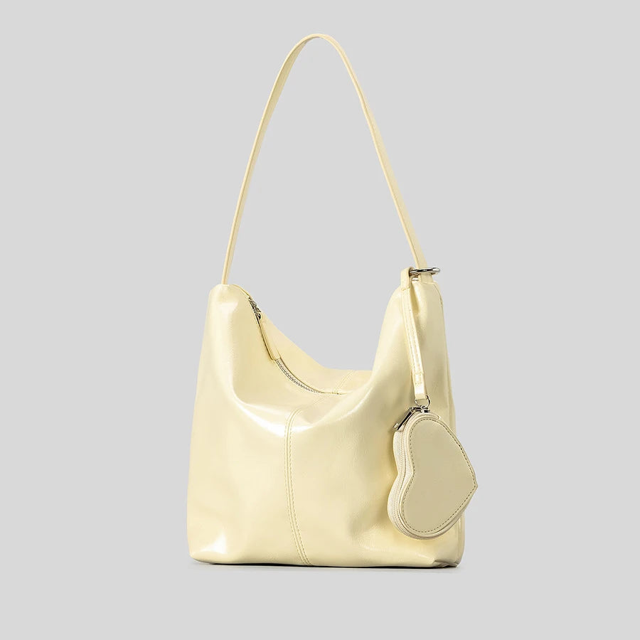 Cream handbag with heart-shaped coin pouch, chic accessory for day or night.