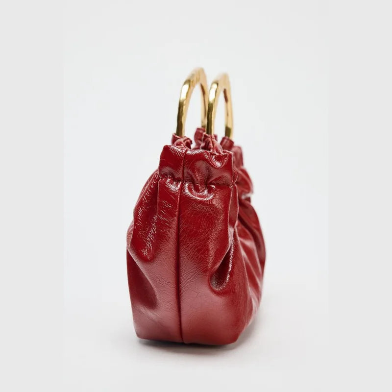 Red leather handbag with gold ring handles, chic accessory for evening events