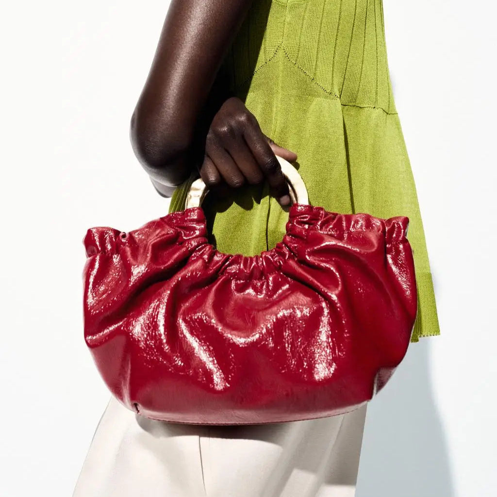 Shiny red handbag with ruched design and wooden handles, chic accessory piece