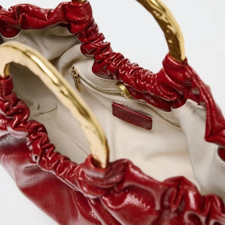 Red leather handbag with gold handles, elegant accessory.
