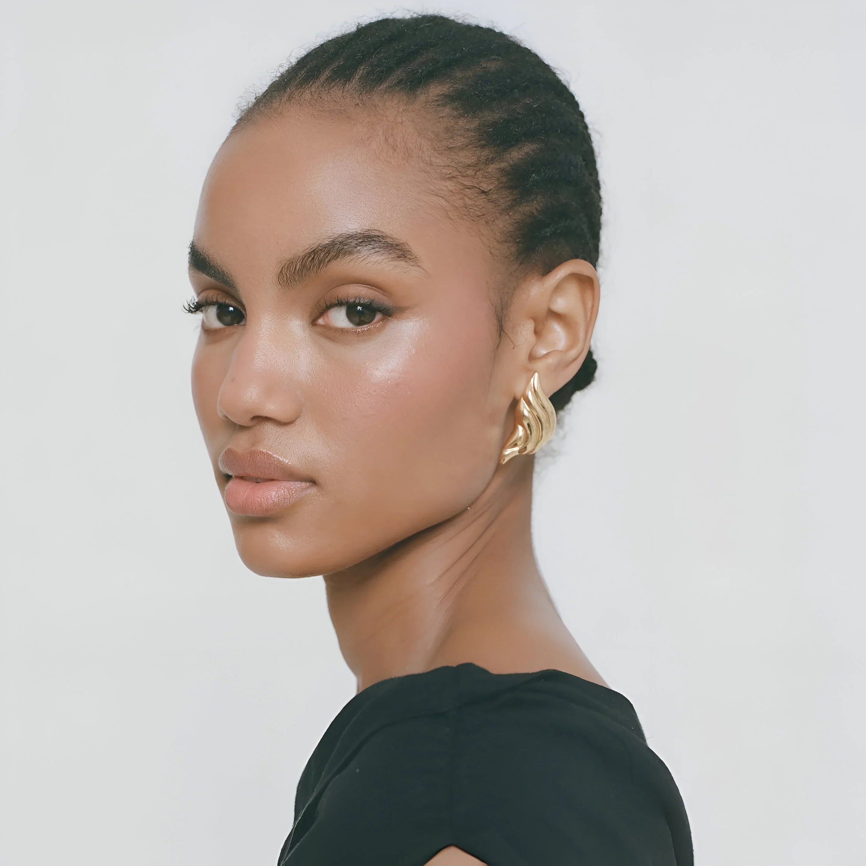 Gold wave-shaped statement earrings, elegant accessory.