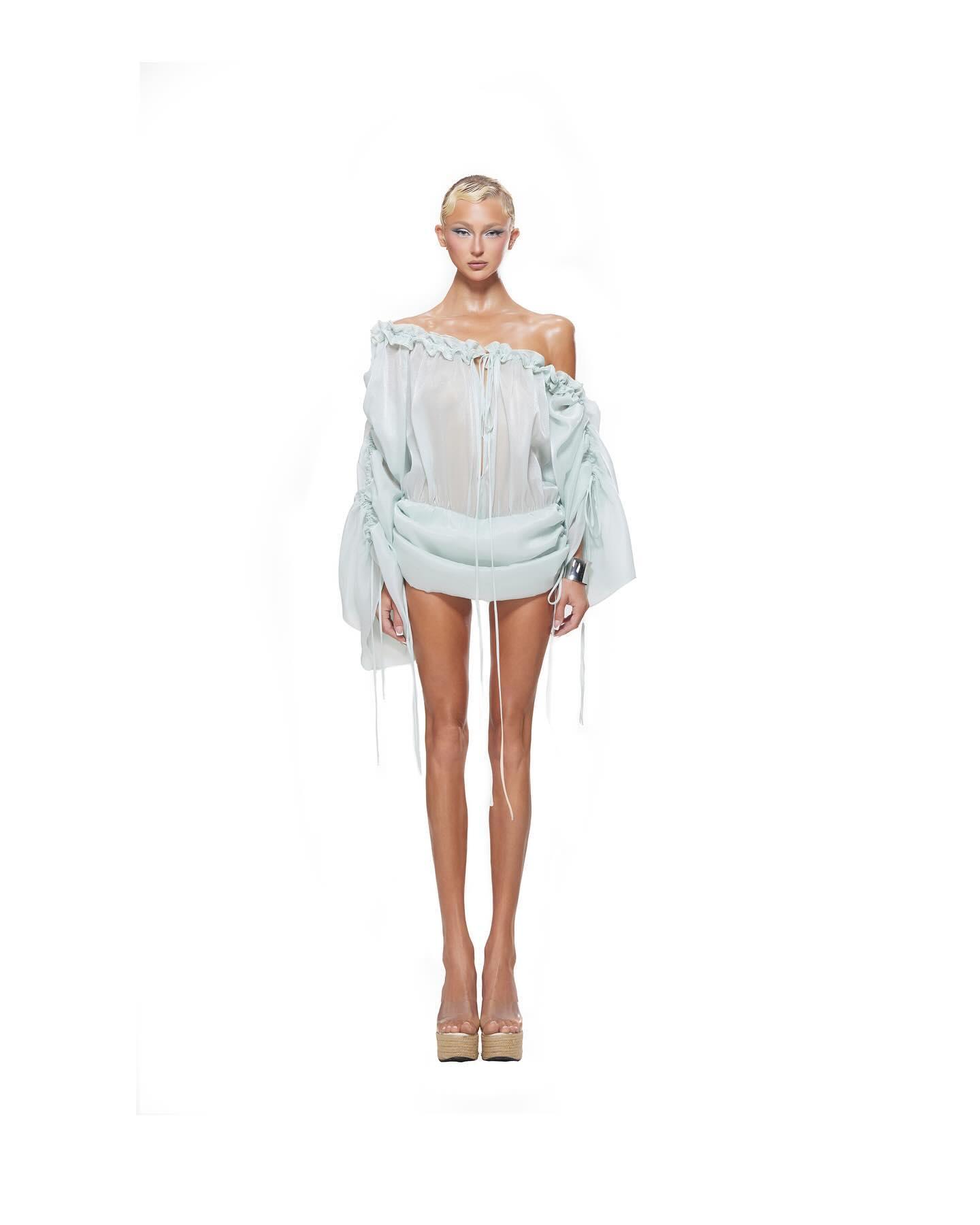 Light blue mini dress with off-the-shoulder neckline, elasticated waist, and gathered details, styled for a chic summer look.