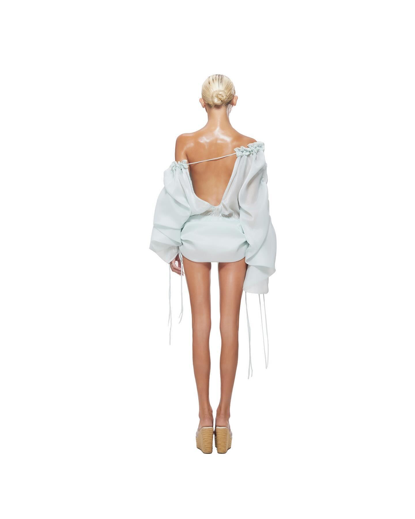 Light blue mini dress with puff sleeves and open back, styled for a chic, summery look. Perfect for warm-weather outings.