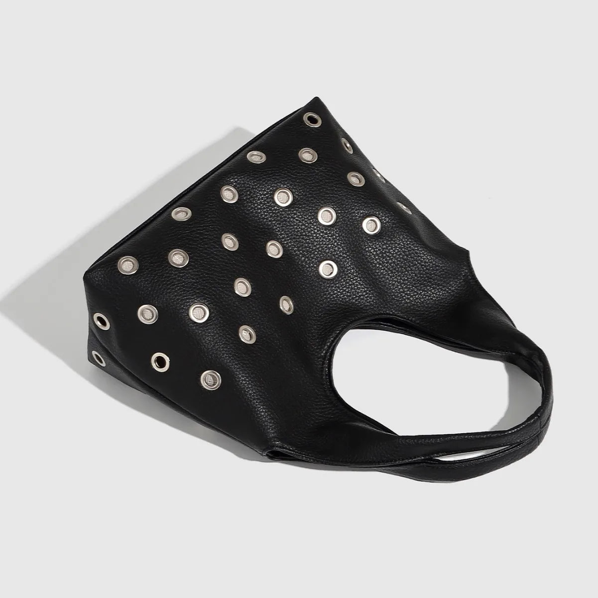 Black leather tote bag with silver metal grommets, edgy fashion accessory.