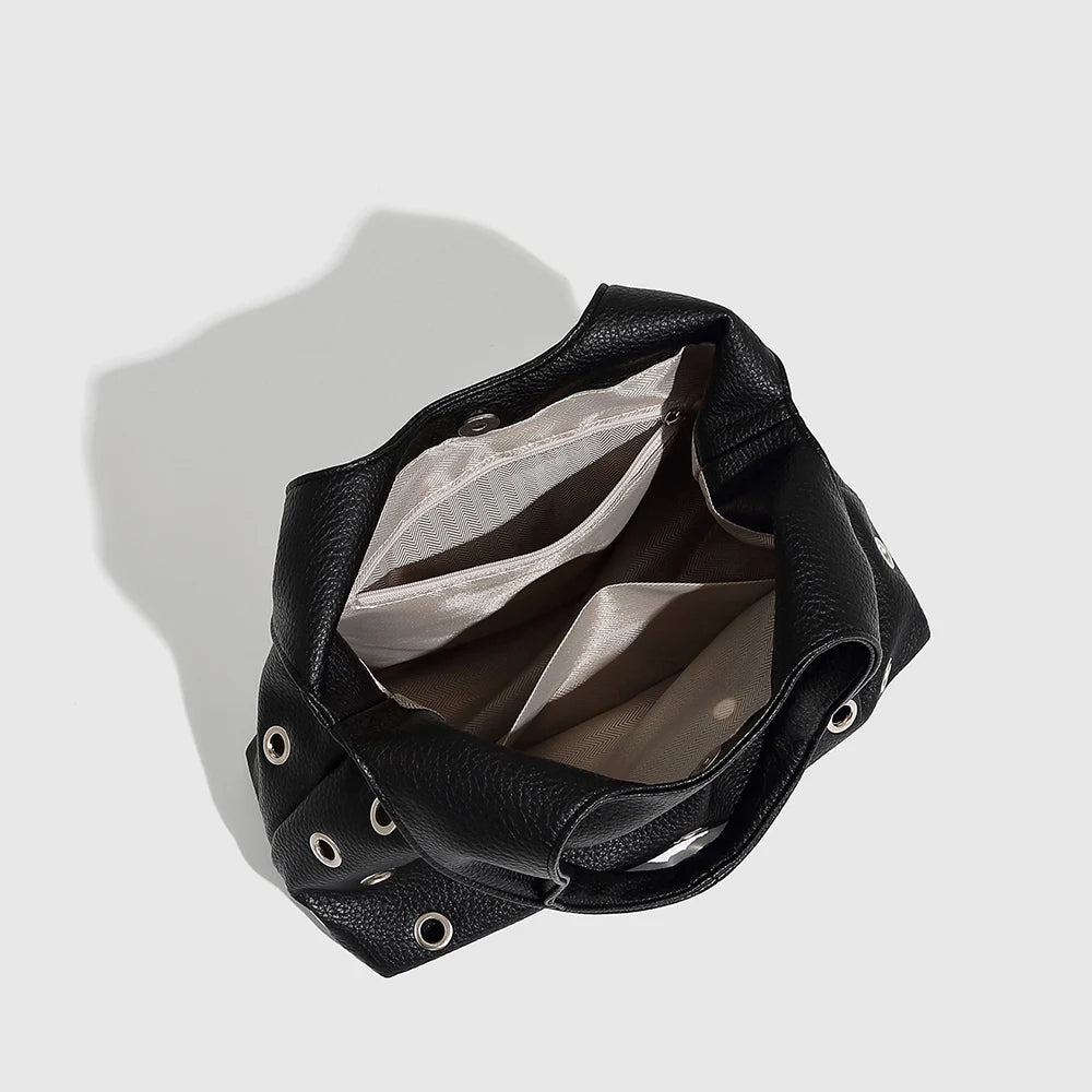 Black leather handbag with grommet details, versatile fashion accessory