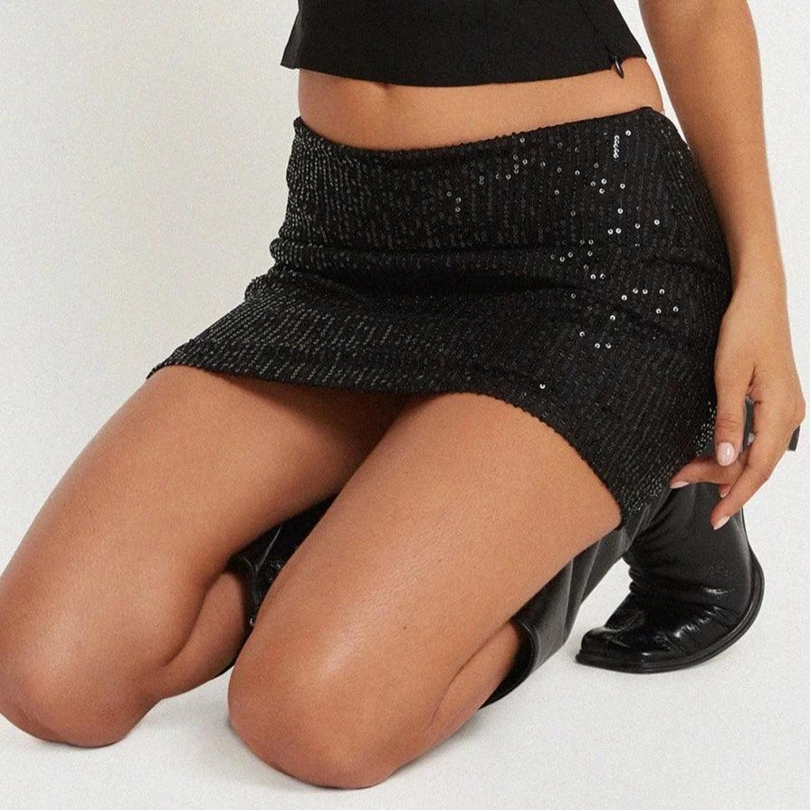 Black sequined mini skirt with a fitted silhouette, styled with a cropped top and knee-high boots. Perfect for evening wear.