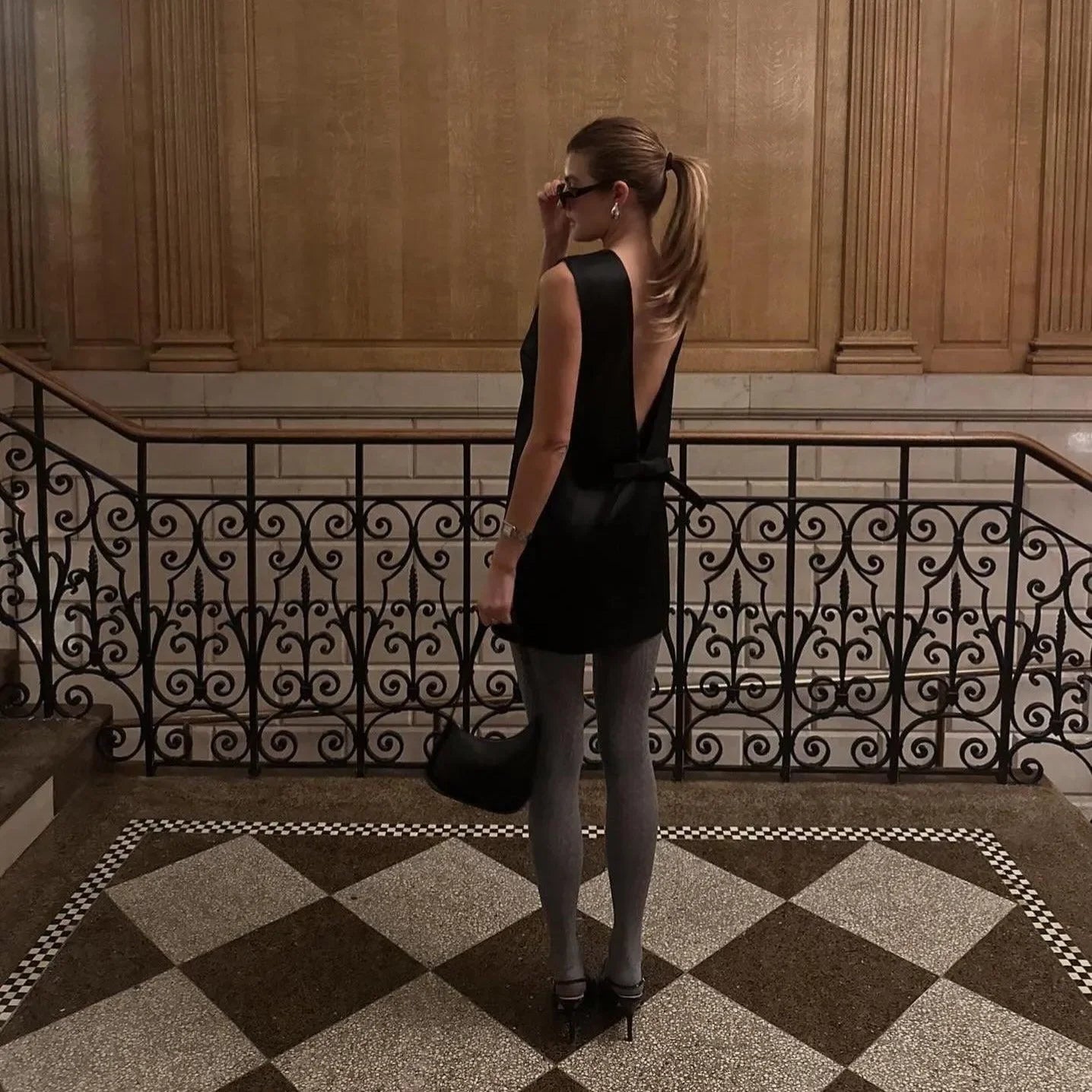 Backless black mini dress with stockings and high heels, chic evening look