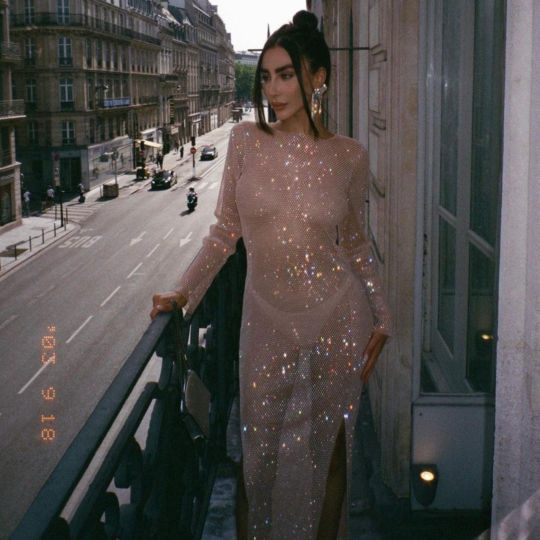 Beige maxi dress adorned with rhinestones, featuring a fitted silhouette and side slit, styled for a chic evening look.