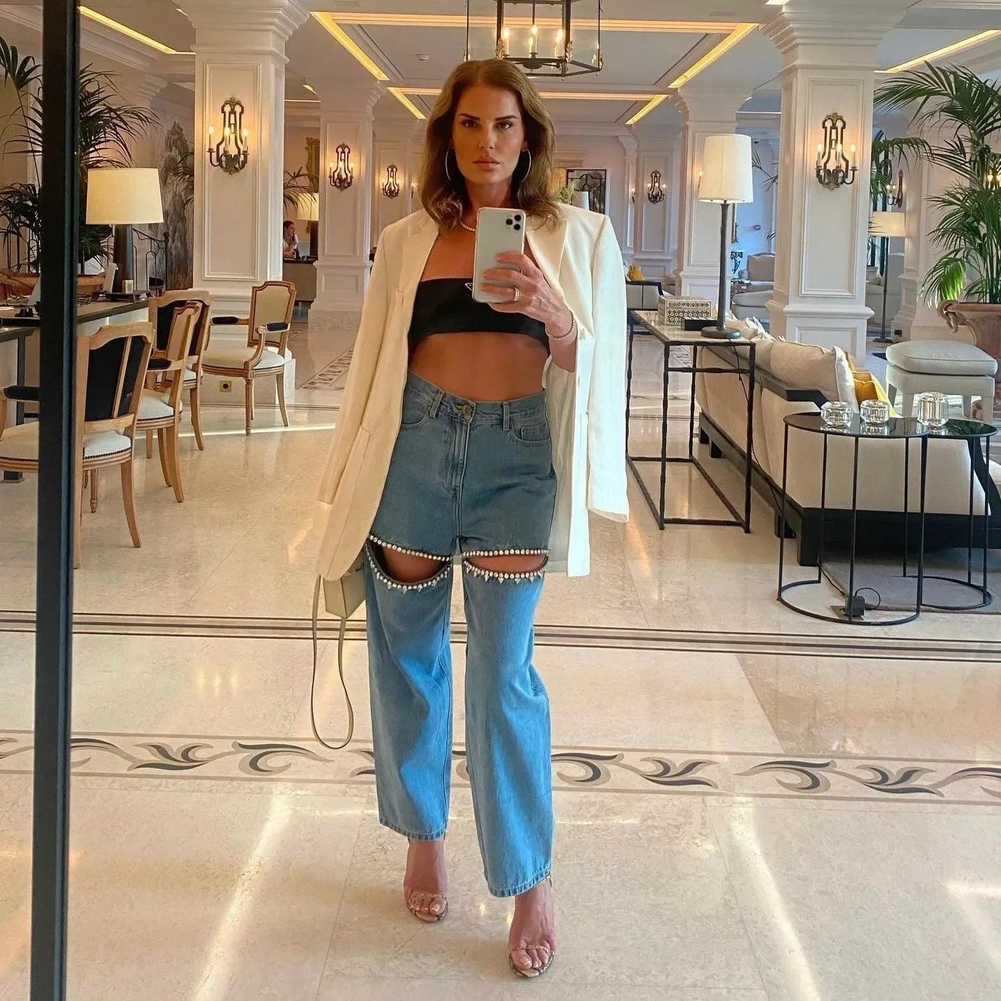Pearl-accented cut-out jeans paired with a bandeau top and oversized white blazer, chic