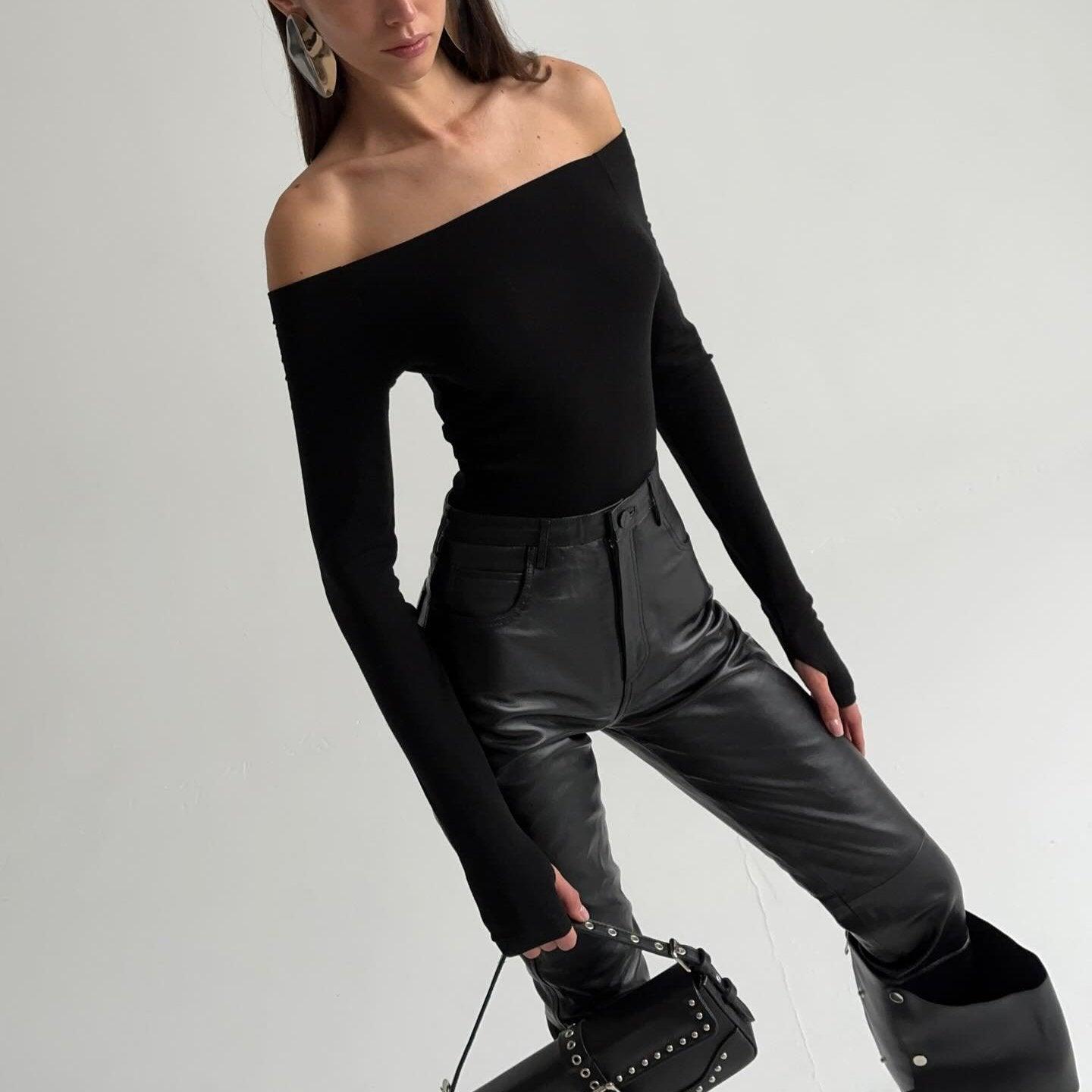 Off-the-shoulder black long-sleeve top with figure-hugging design, paired with high-waisted leather