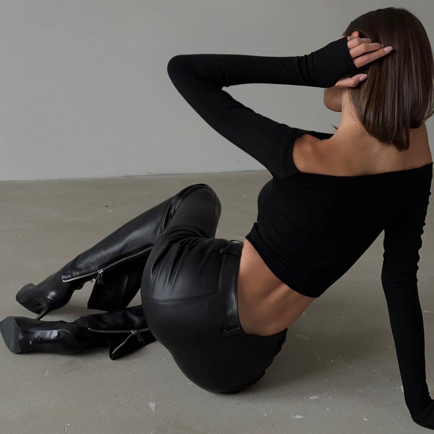 One-shoulder black top with long sleeves, paired with black leather pants, edgy night-out style.