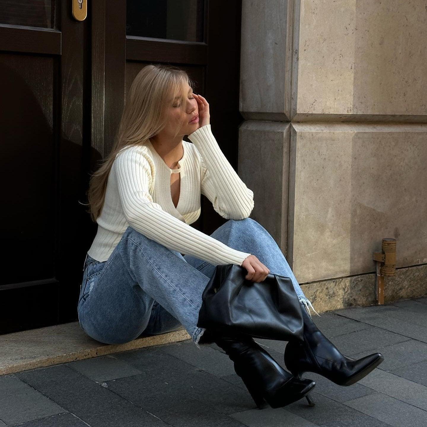 Ribbed knit long-sleeve sweater with cutout detail, paired with casual jeans and black knee-high