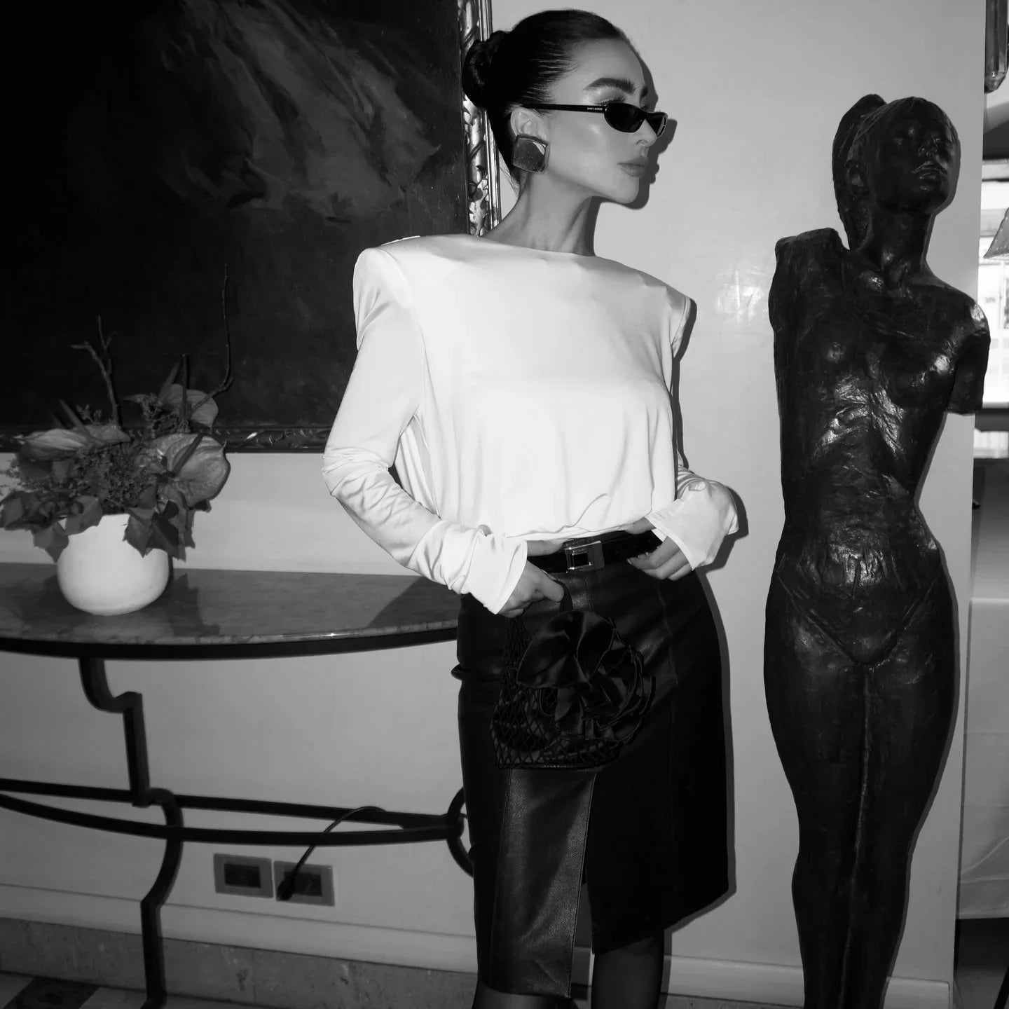 Long-sleeve satin blouse with structured shoulders, paired with a high-waist leather skirt,