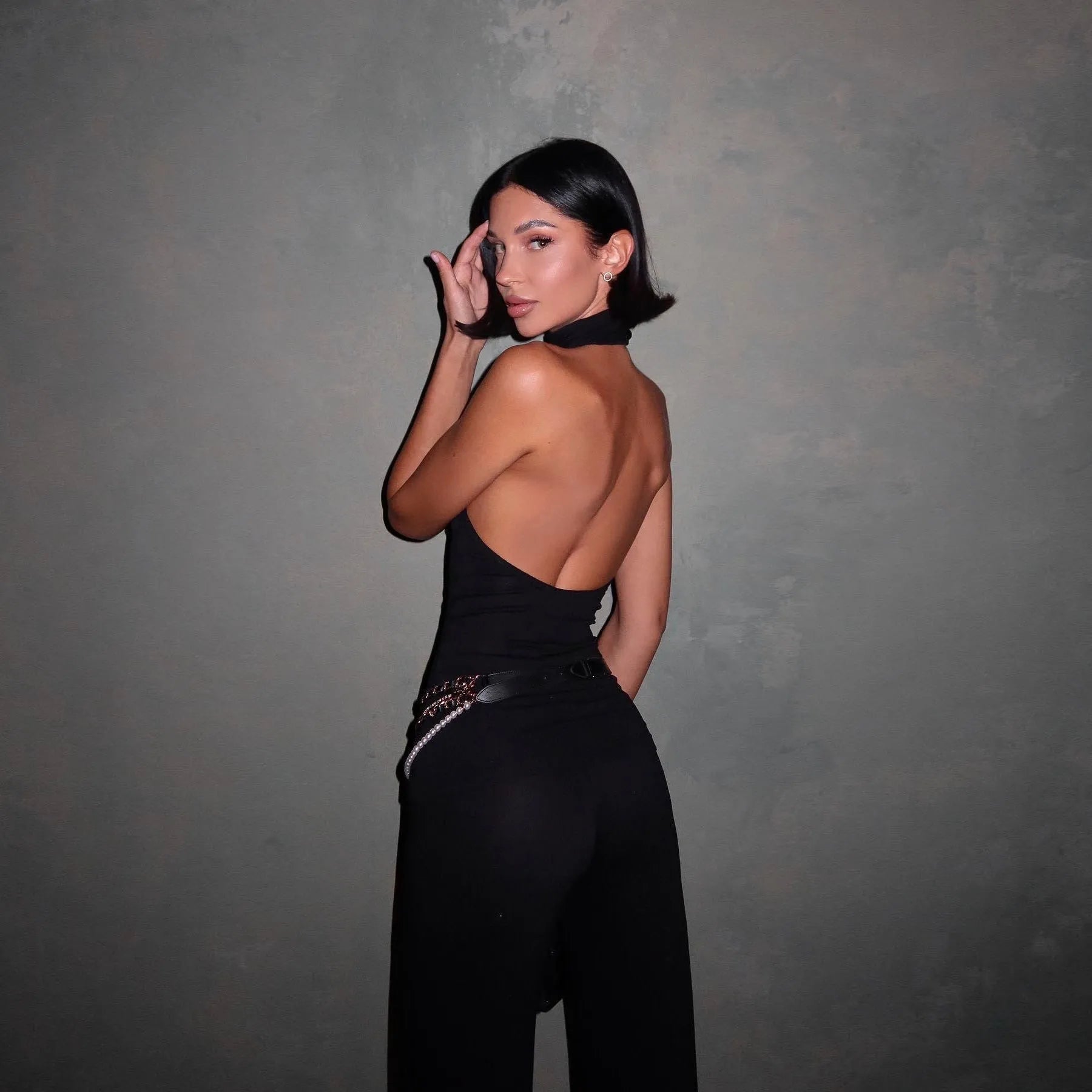 Backless black halter jumpsuit with chain belt, stylish eveningwear.