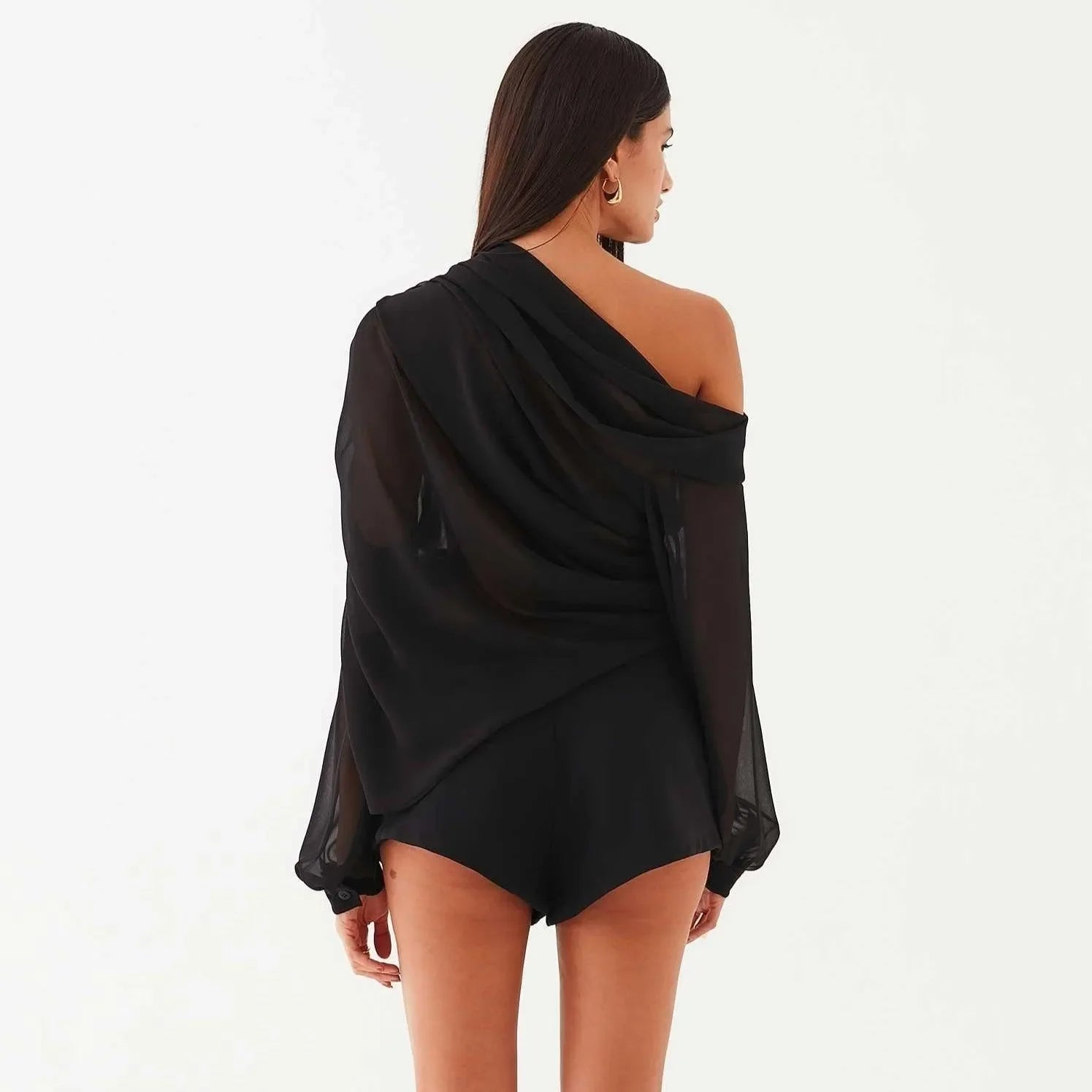 Black asymmetrical draped blouse with flowing sleeves, styled off one shoulder for an elegant, chic look.