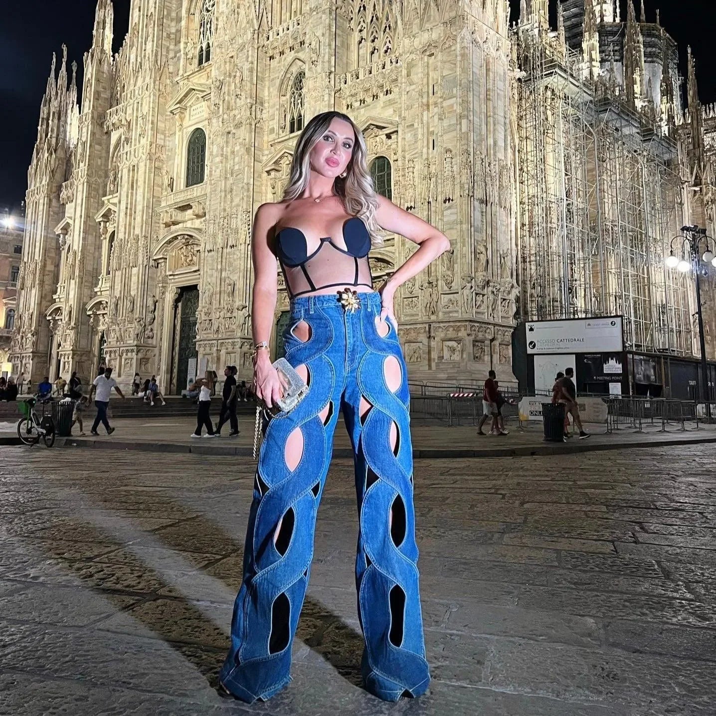 Cut-out denim pants styled with black bandeau top, bold night-out outfit