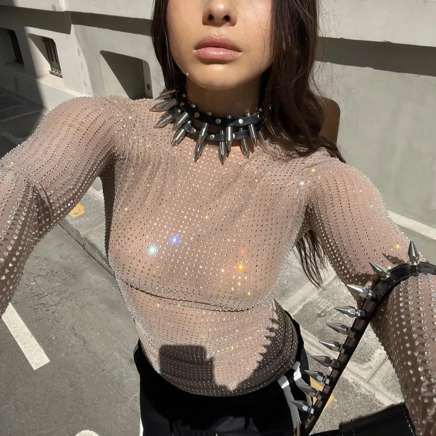 Sheer rhinestone-studded mesh top paired with a spiked choker necklace, suitable for a
