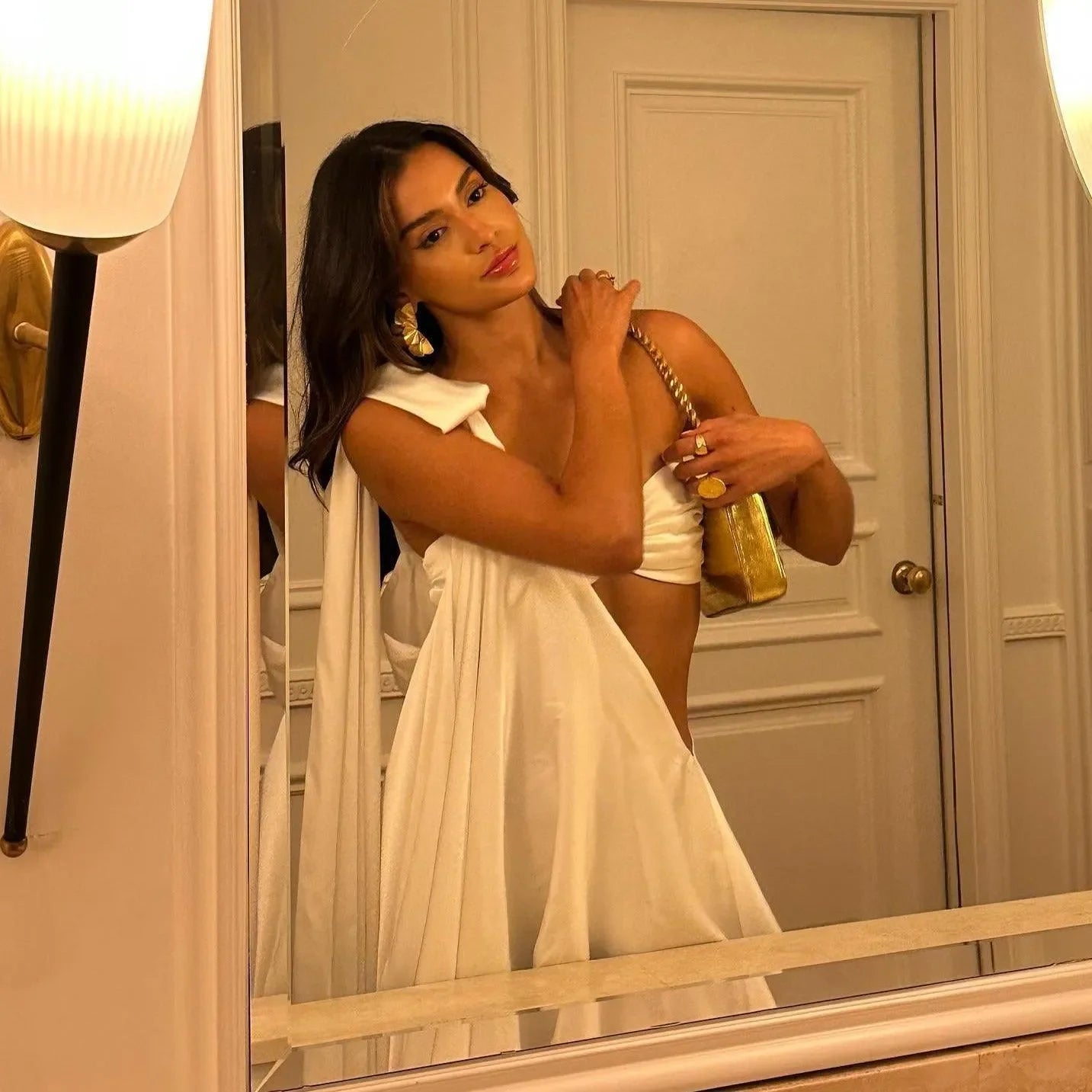 One-shoulder white satin dress with gold handbag, elegant evening look