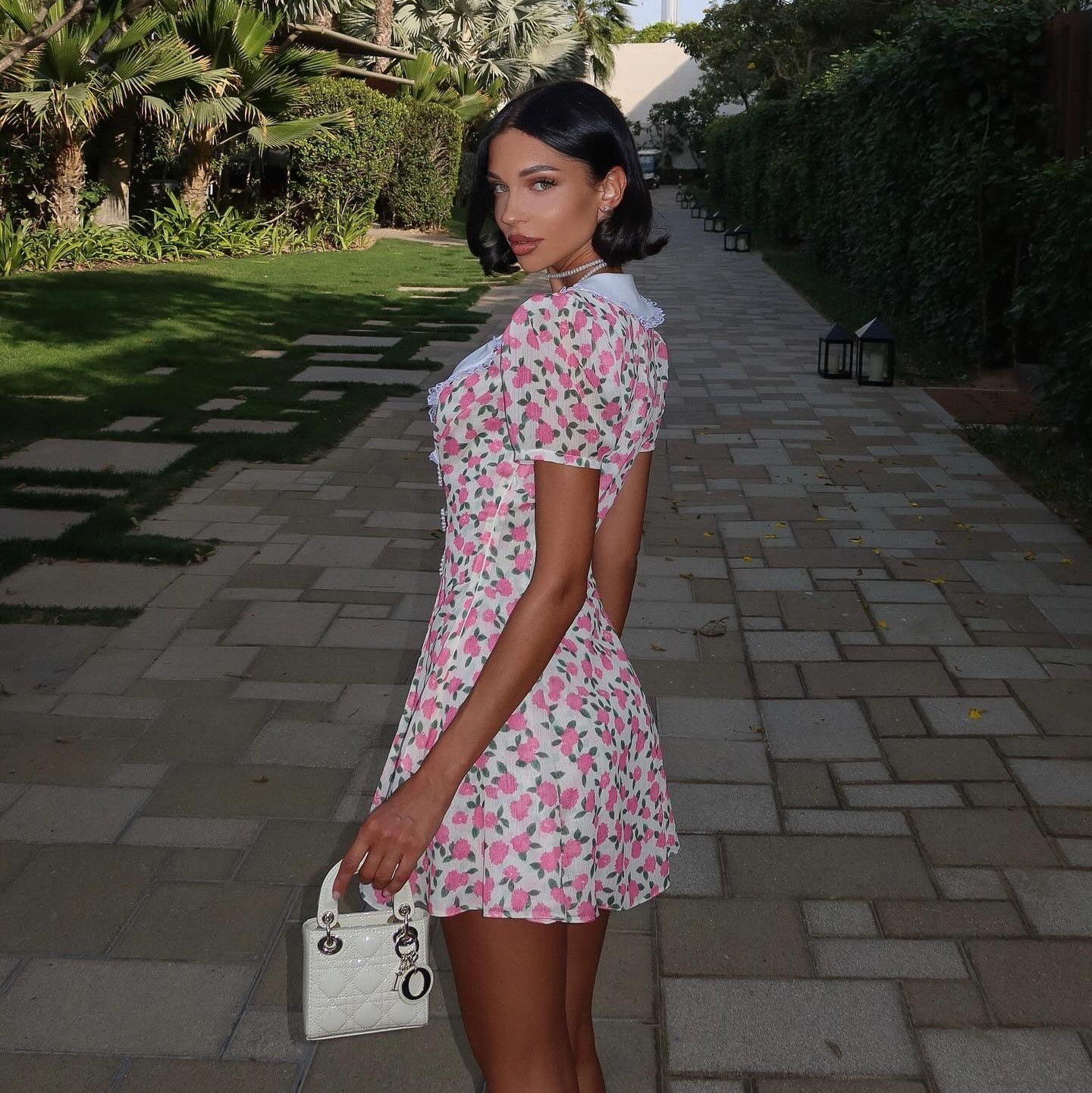 Pink vintage mini dress with polka dots, featuring a peter pan collar, styled with a chic handbag for a playful look.