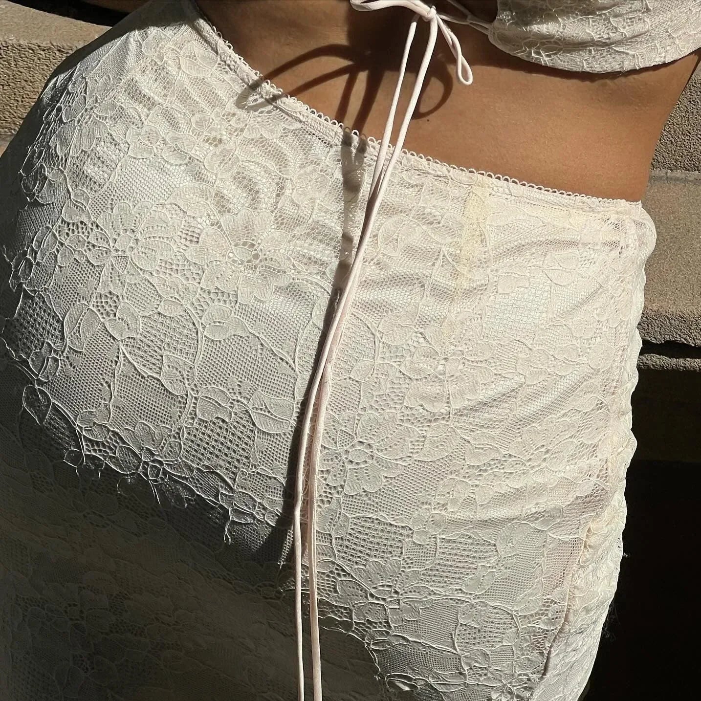 White lace crop top with tie detail, party-ready look.