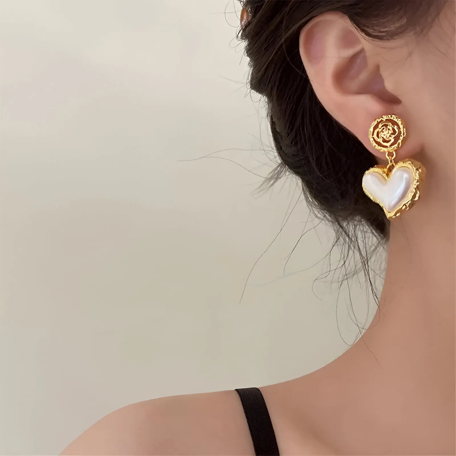 Gold-tone earrings with heart-shaped pearl detail, elegant accessory.