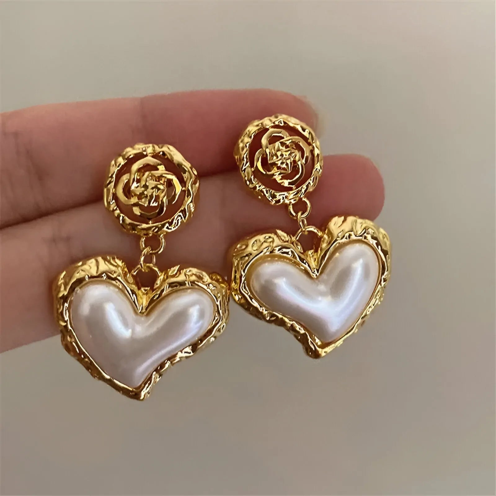 Gold heart-shaped pearl earrings.