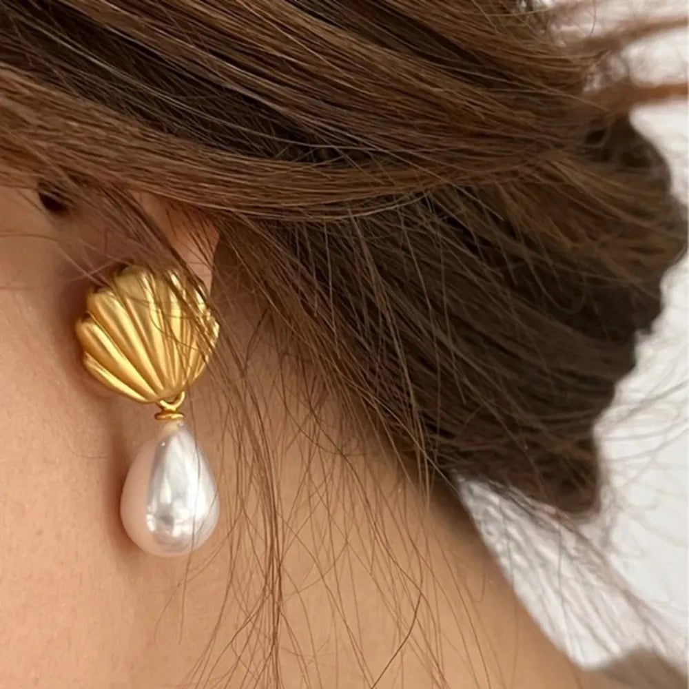 Shell-shaped gold and pearl drop earrings, elegant jewelry piece.