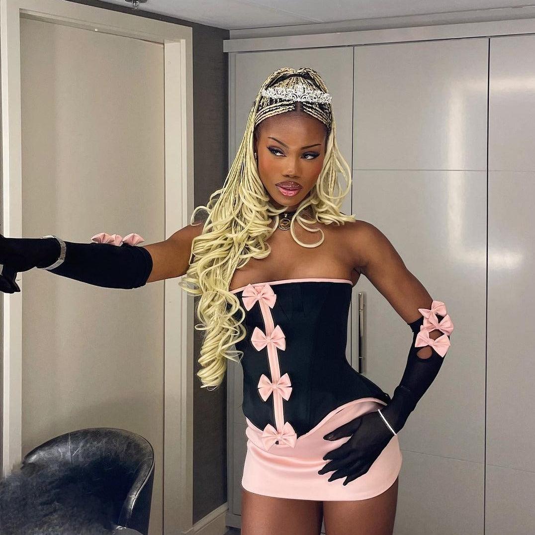 Strapless mini dress with pink bow details and black gloves, statement party outfit.