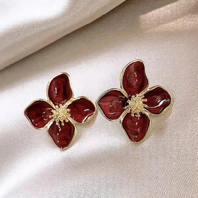 Red enamel flower earrings with gold trim, statement accessory.