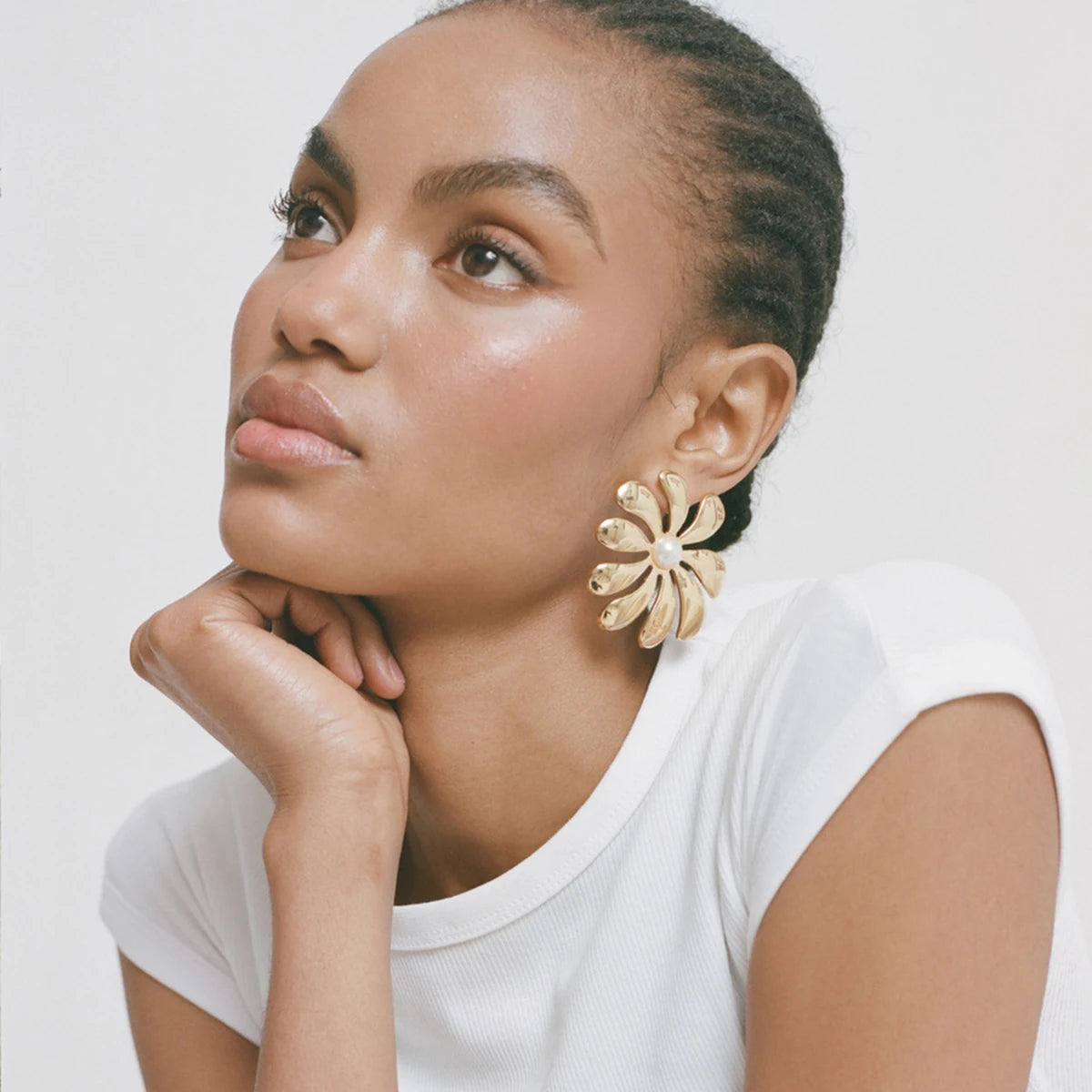 Gold flower-shaped earrings with central pearl, bold statement accessory