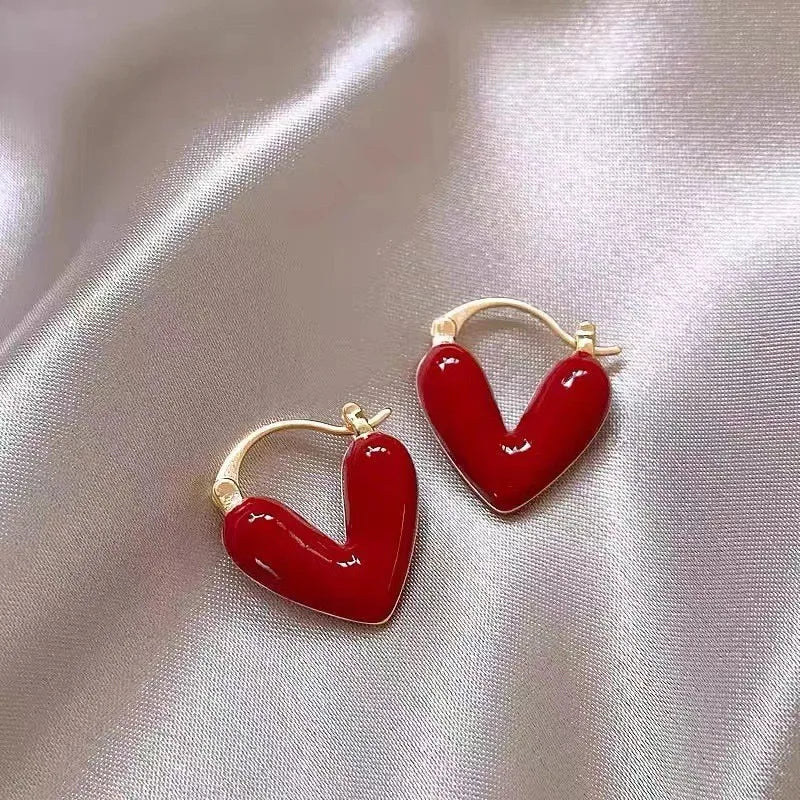 red heart-shaped hoop earrings on satin background